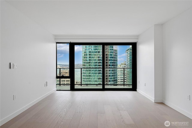 300 Virginia St Unit 1710, Seattle, WA 98101 - spare room with a city view, baseboards, wood finished floors, and a healthy amount of sunlight