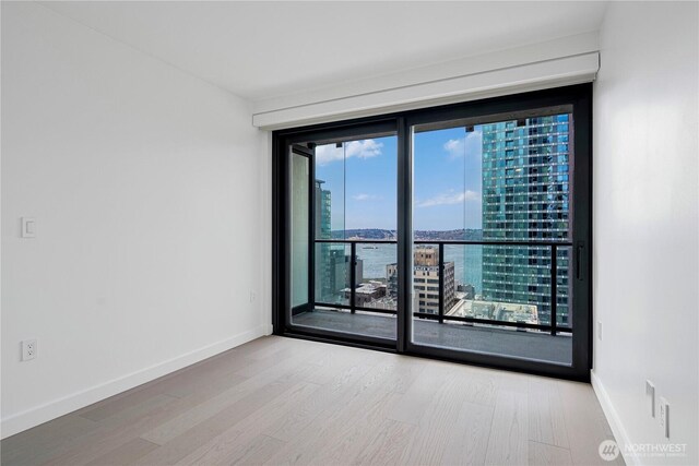 300 Virginia St Unit 1710, Seattle, WA 98101 - empty room featuring wood finished floors, a view of city, and baseboards