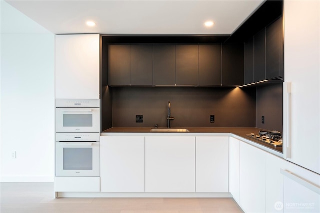 300 Virginia St Unit 1710, Seattle, WA 98101 - kitchen featuring white cabinets, modern cabinets, a sink, double oven, and stainless steel gas stovetop
