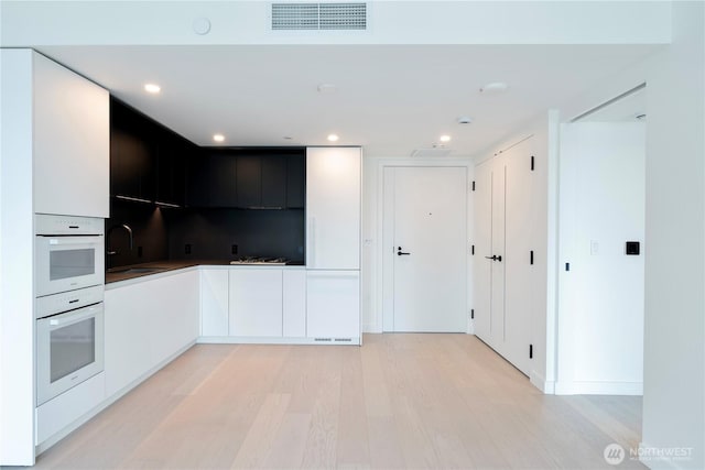 300 Virginia St Unit 1710, Seattle, WA 98101 - kitchen with modern cabinets, light wood-style flooring, white cabinetry, visible vents, and a sink