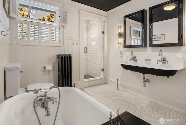 bathroom with radiator, a wainscoted wall, a sink, a soaking tub, and a stall shower