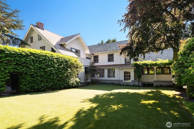 rear view of property featuring a lawn and a chimney