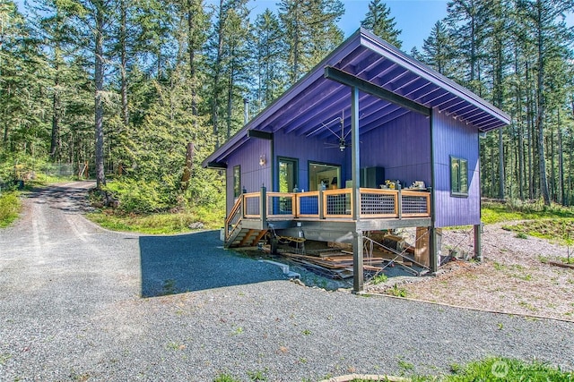 view of front of property with a deck and a view of trees