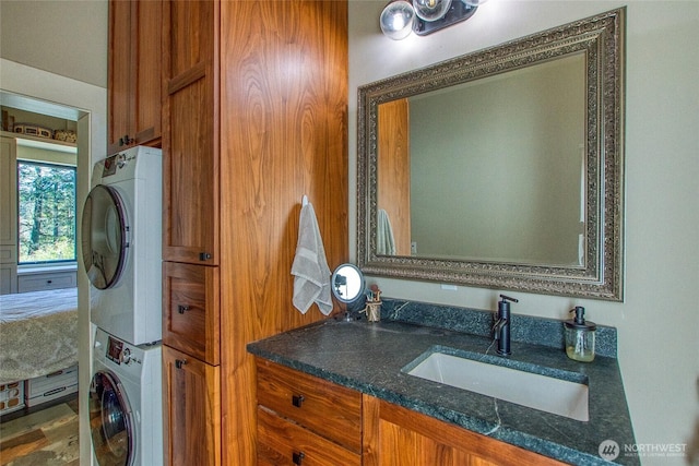 laundry room with stacked washer / dryer and a sink