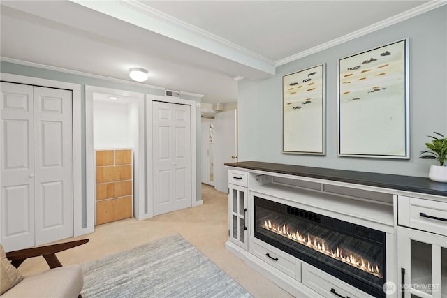 living area featuring light colored carpet, crown molding, a glass covered fireplace, and visible vents
