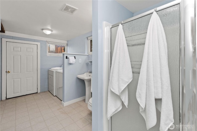 full bath with visible vents, toilet, a sink, washer and dryer, and a stall shower