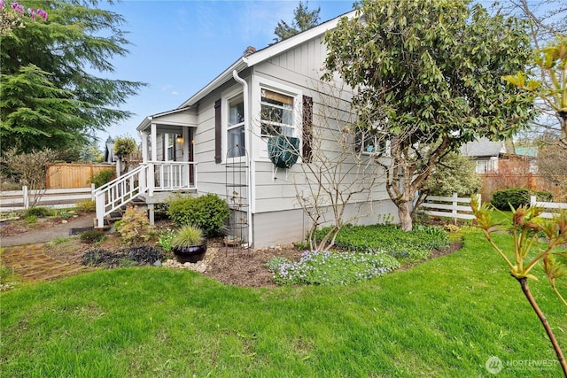 view of side of home featuring a lawn and fence