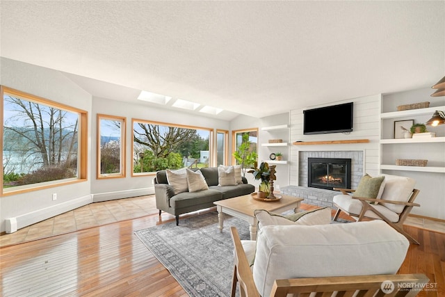 1016 Coronado Ave, Bellingham, WA 98229 - living area with a textured ceiling, light wood-style flooring, baseboards, vaulted ceiling, and a brick fireplace