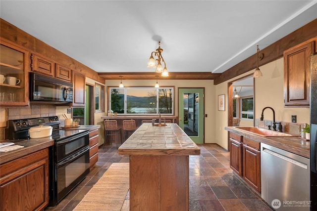 1016 Coronado Ave, Bellingham, WA 98229 - kitchen featuring decorative backsplash, a sink, stone tile flooring, a center island, and black appliances