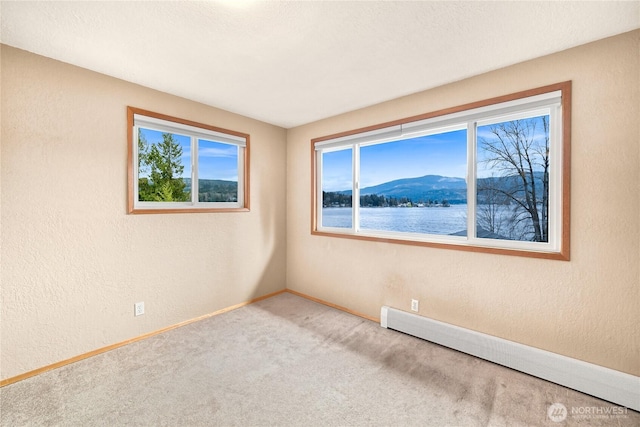 1016 Coronado Ave, Bellingham, WA 98229 - carpeted empty room featuring a baseboard radiator, a textured wall, a mountain view, and baseboards