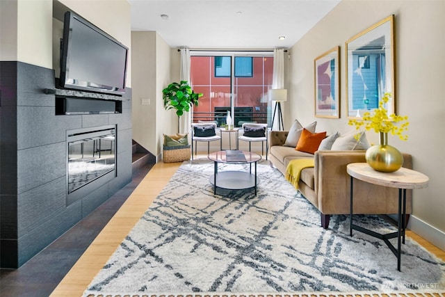 living room with a glass covered fireplace, baseboards, and wood finished floors