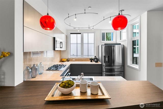kitchen featuring tasteful backsplash, appliances with stainless steel finishes, a sink, and hanging light fixtures
