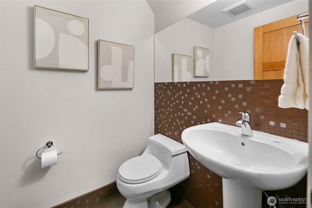 half bathroom featuring toilet, a sink, and visible vents