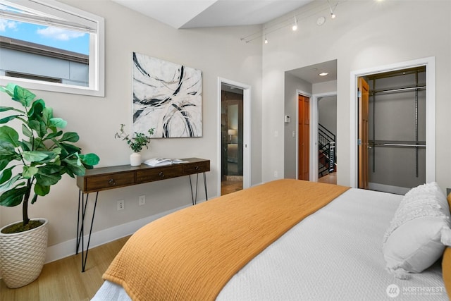 bedroom featuring baseboards, high vaulted ceiling, and wood finished floors