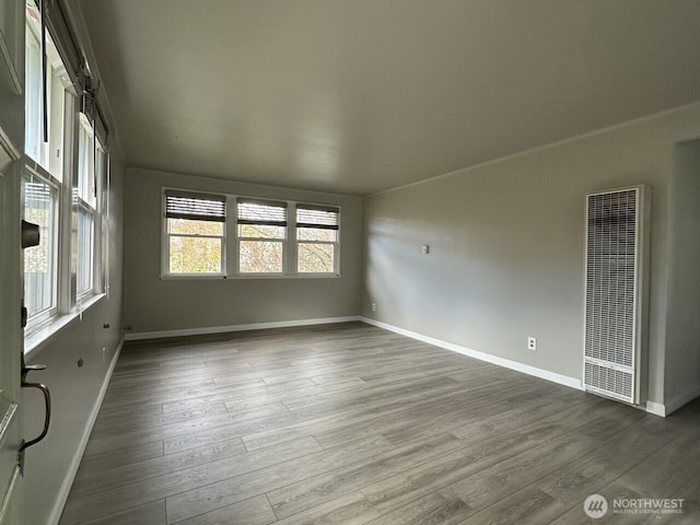 empty room featuring baseboards, a heating unit, and wood finished floors