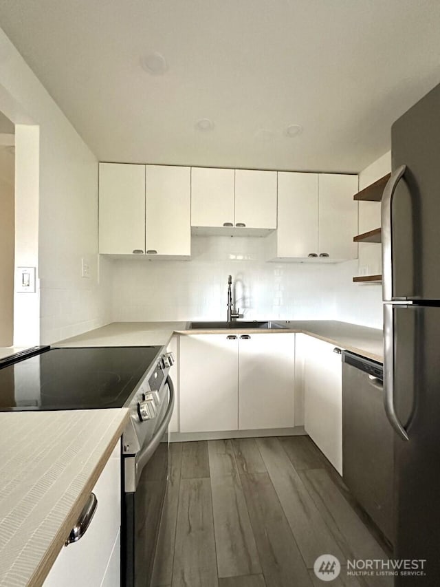 kitchen with white cabinets, open shelves, appliances with stainless steel finishes, light wood-type flooring, and decorative backsplash