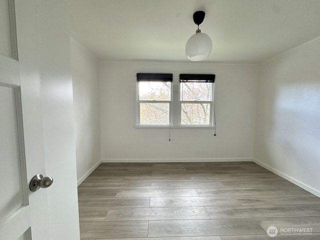 unfurnished room featuring baseboards and light wood-style floors