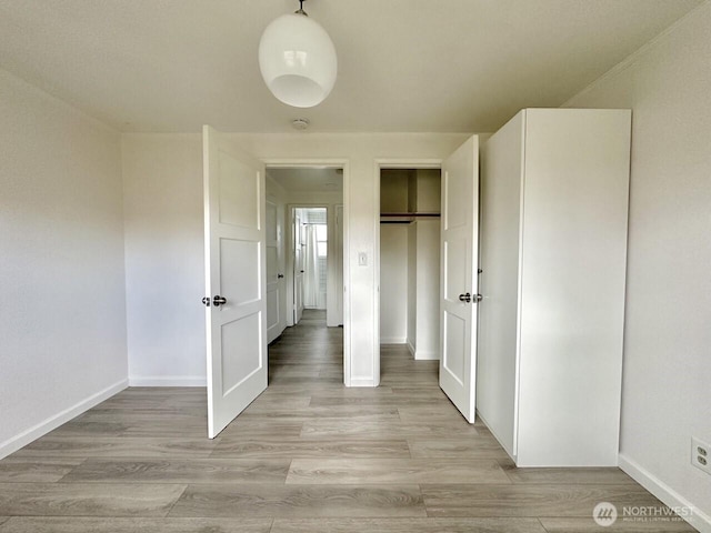 unfurnished bedroom featuring light wood-style floors, a closet, and baseboards