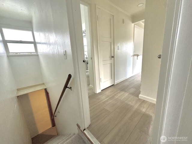 hallway with baseboards, an upstairs landing, and wood finished floors