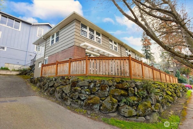 view of property exterior featuring fence and brick siding