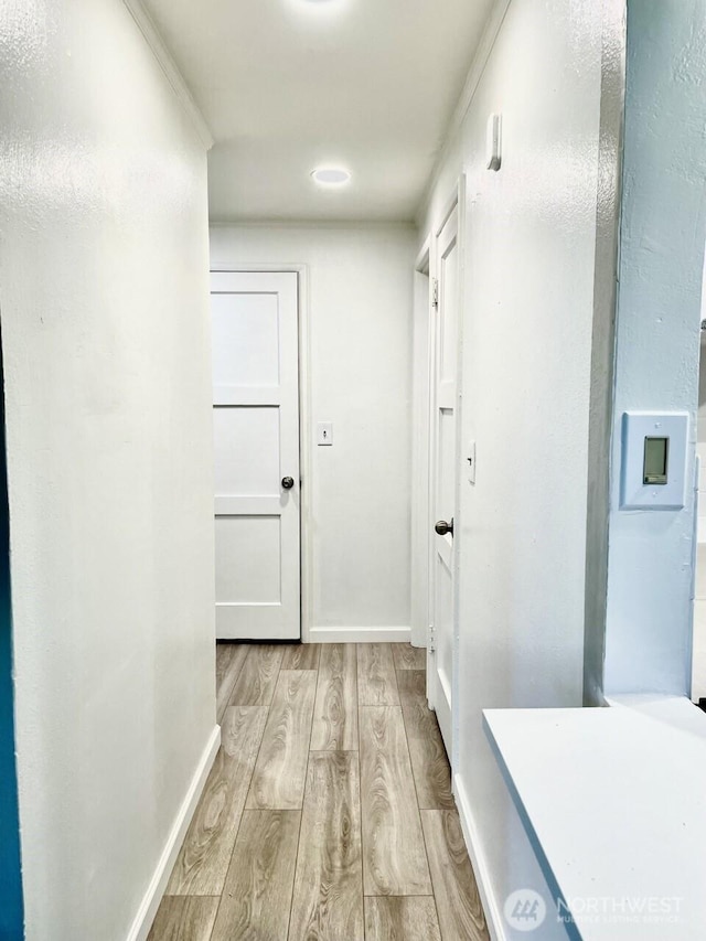 corridor with light wood-style flooring and baseboards