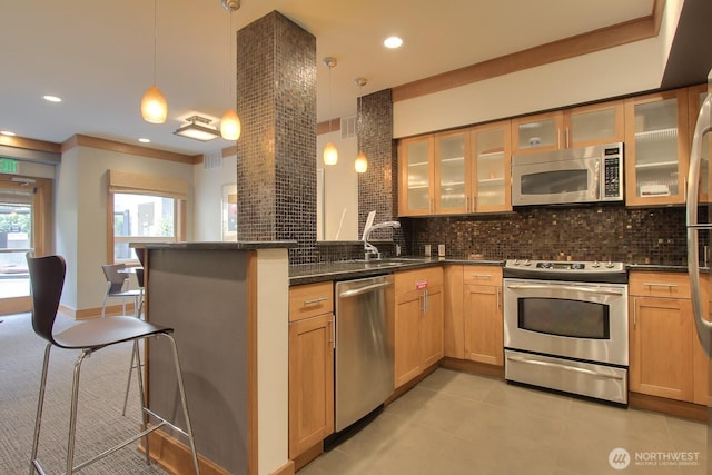 kitchen with a peninsula, appliances with stainless steel finishes, decorative backsplash, and a sink