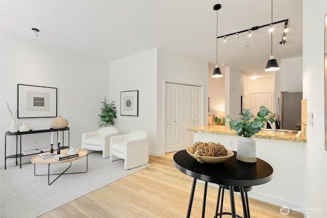 kitchen featuring freestanding refrigerator, a peninsula, baseboards, and light wood-style floors