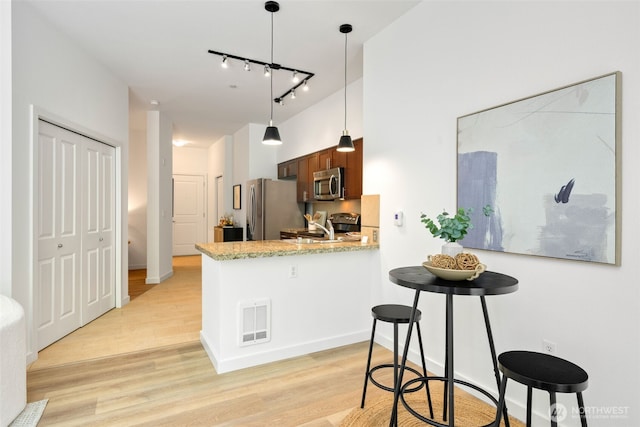 kitchen with visible vents, a peninsula, rail lighting, light wood-style flooring, and appliances with stainless steel finishes