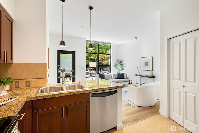 kitchen featuring a sink, dishwasher, a peninsula, open floor plan, and pendant lighting