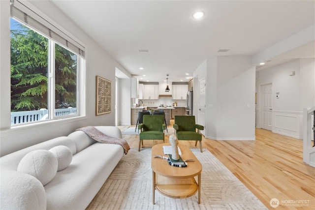 living room featuring baseboards, recessed lighting, and light wood-style floors
