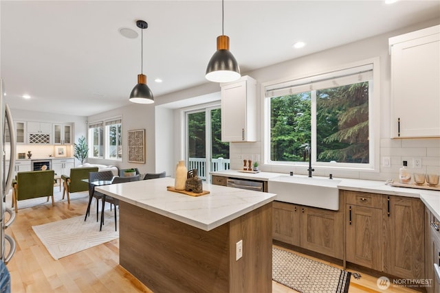 kitchen featuring a center island, a sink, light wood-style floors, pendant lighting, and decorative backsplash
