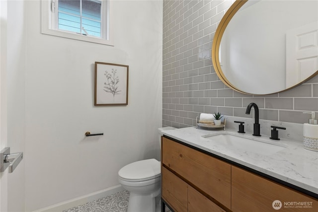 bathroom featuring toilet, vanity, baseboards, and backsplash