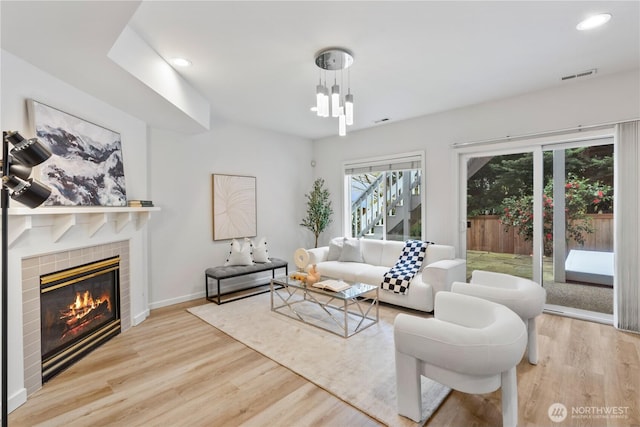 living room featuring recessed lighting, a tiled fireplace, visible vents, and wood finished floors