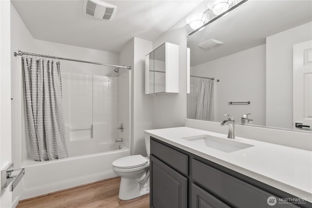 bathroom featuring vanity, toilet, visible vents, shower / bath combo with shower curtain, and wood finished floors