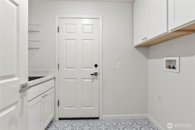 clothes washing area with baseboards, hookup for a washing machine, and cabinet space