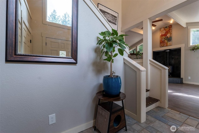 interior space featuring baseboards, stone finish flooring, and a tiled fireplace