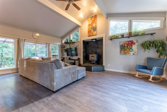 living room with high vaulted ceiling, ceiling fan, wood finished floors, and a wood stove
