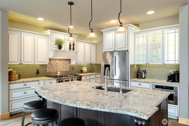 kitchen featuring appliances with stainless steel finishes, a sink, a breakfast bar, backsplash, and recessed lighting