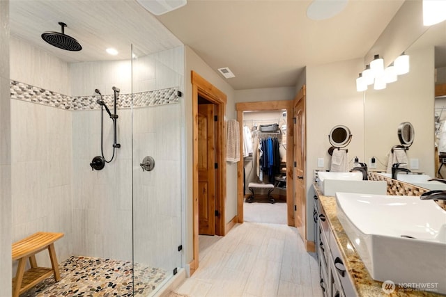 bathroom featuring a walk in shower, double vanity, and a spacious closet