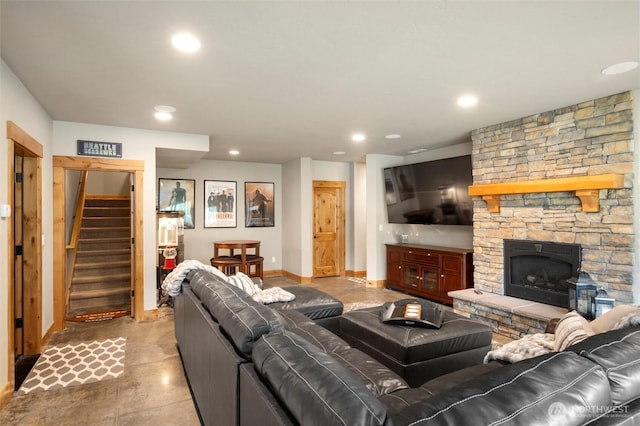 living area featuring stairway, baseboards, recessed lighting, finished concrete flooring, and a stone fireplace