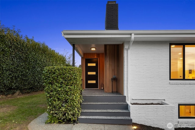 entrance to property with brick siding and a chimney