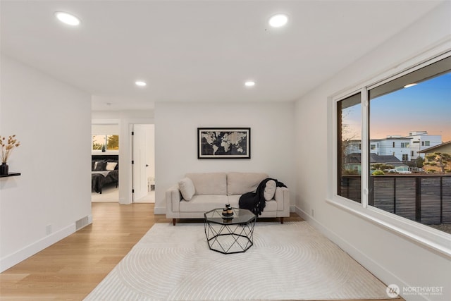 living room featuring recessed lighting, baseboards, and light wood-style flooring