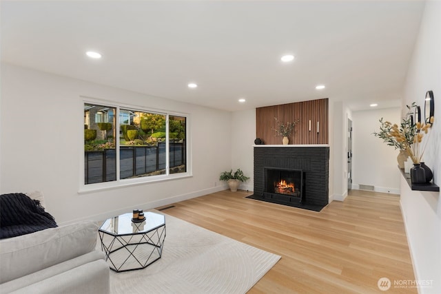living area featuring light wood-style floors, a fireplace, recessed lighting, and visible vents