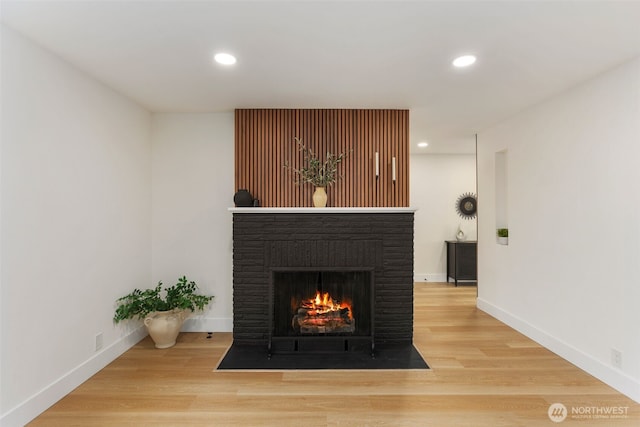 details featuring baseboards, recessed lighting, wood finished floors, and a fireplace