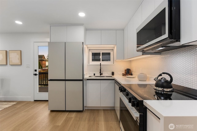 kitchen featuring a sink, decorative backsplash, fridge, and black range with electric cooktop