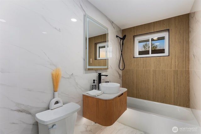 full bath featuring vanity, marble finish floor, tub / shower combination, toilet, and tile walls
