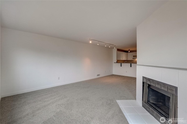 24762 45th Ave S Unit 12-D1, Kent, WA 98032 - unfurnished living room with carpet flooring, a tiled fireplace, and baseboards