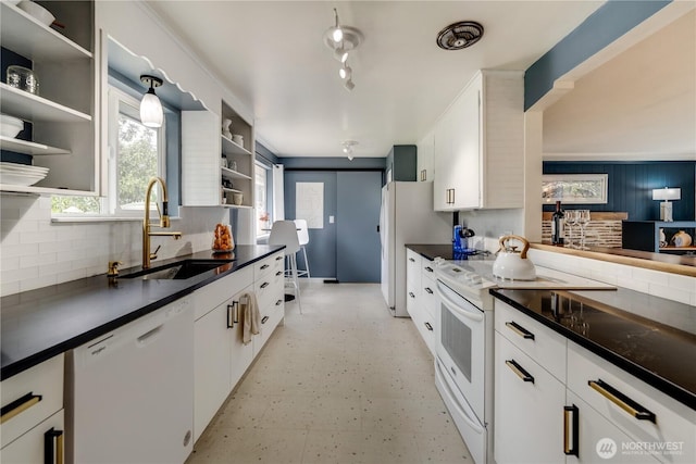 kitchen with dark countertops, tasteful backsplash, open shelves, a sink, and white appliances