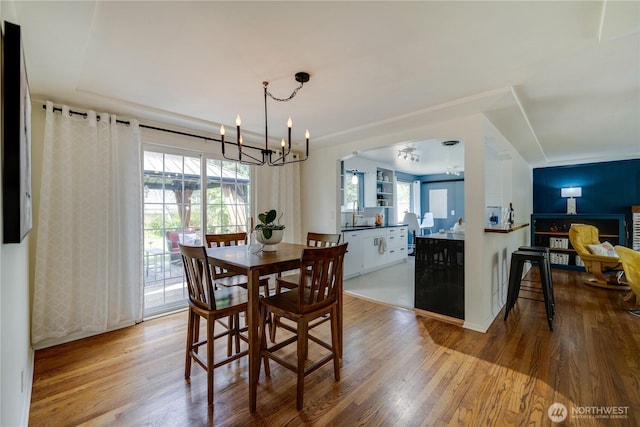 dining area featuring arched walkways, wood finished floors, and a chandelier