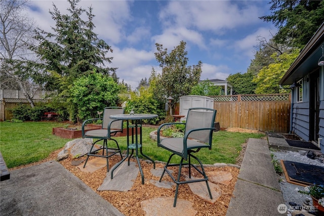 view of patio / terrace with an outdoor structure, a fenced backyard, and a storage unit